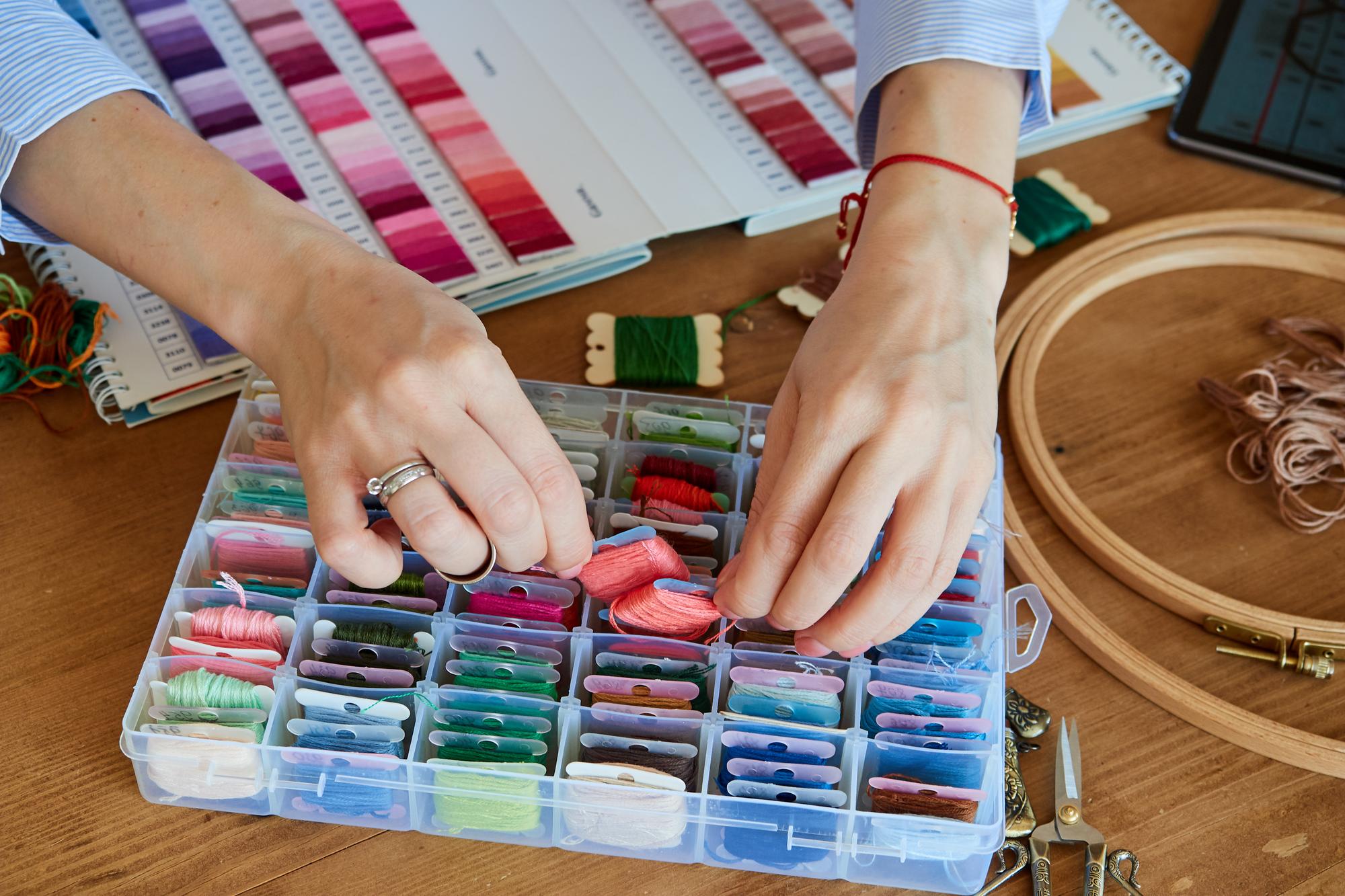 Artisan arranging embroidered samples on table